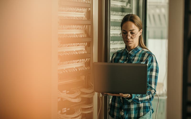 woman using laptop in server room