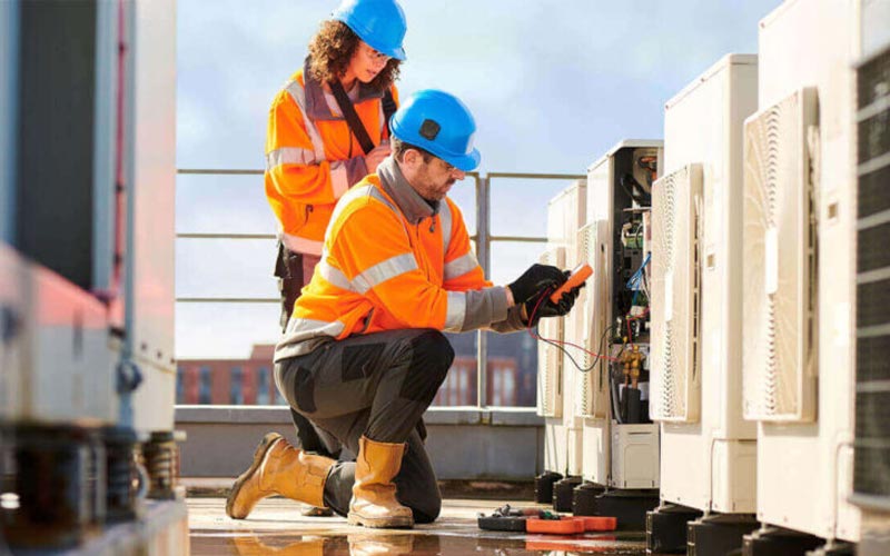 technicians checking condensing unit on rooftop