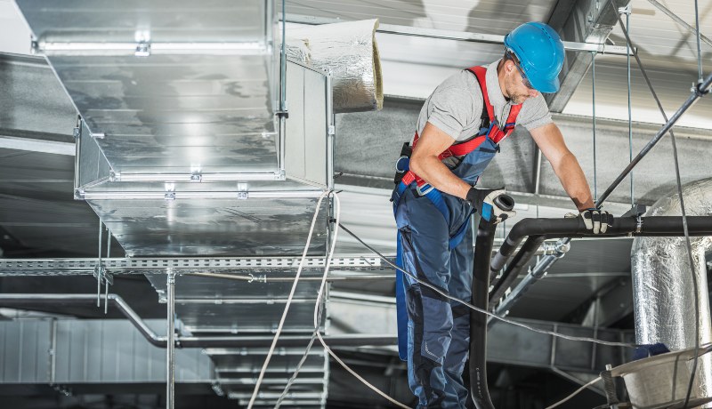 An HVAC worker inspects and repairs the air duct system of a commercial HVAC in DuPage County, IL